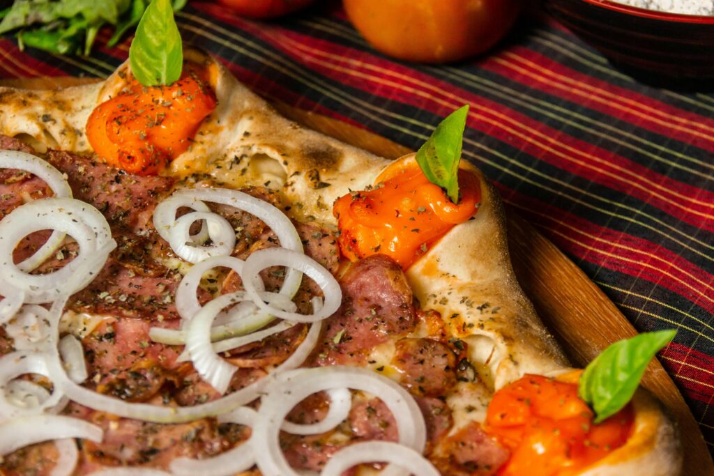 Buffet Bestellen, a pizza with onions and peppers on a wooden plate